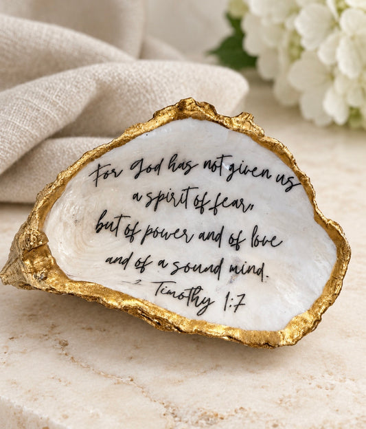 Gold-edged oyster shell featuring 2 Timothy 1:7 in black script